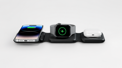 Front eye-level view of the PrimeSync black foldable travel charger actively powering three premium Apple devices simultaneously: an iPhone showing a green charging battery capsule, an Apple Watch on the center puck, and AirPods Pro on the right pad.